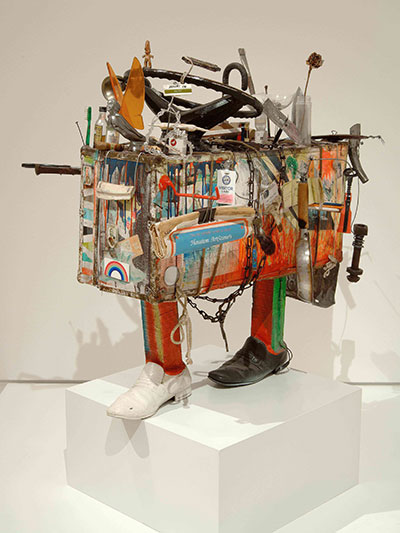 Bert L. Long, Jr.  Quest, 1983  Acrylic on suitcase with frying pan, shoes, glass, liquor bottles,  orange peel, name tag, credit card, chain, rope, steering wheel,  wood, newspaper, bone, keys, harmonica, toothbrush, and  other mixed media Image courtesy Deborah Colton Gallery 