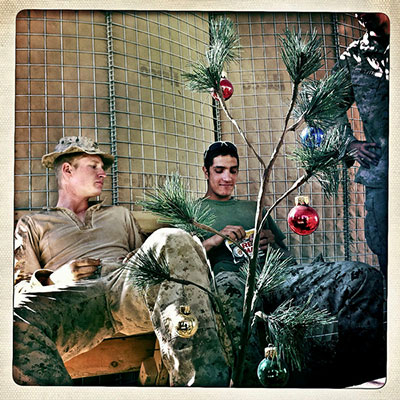 US Marines from Bravo Company's Third Platoon, with the First Battalion, Eighth Marines, sitting around a Christmas tree with Female Engagement Team members at the Sher Ghazi base in Helmand Province, Afghanistan, on November 9, 2010. Note that these images combine four separate photographs and that only one Christmas tree actually existed. 