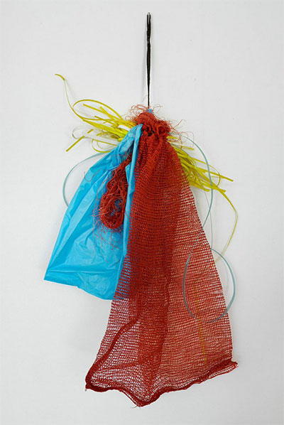 Tony Feher, Preliminary Aspect, 2001 Red onion bag with black draw string, blue plastic tee shirt bag and blue, white, and yellow plastic strapping 36 x 26 1/2 x 4 Courtesy Hiram Butler Gallery.