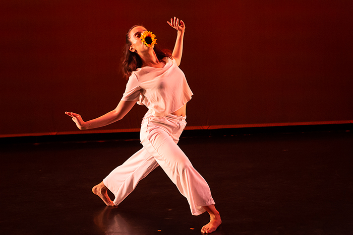Paty Lorena Solórzano dancing with a sunflower against a red backdrop