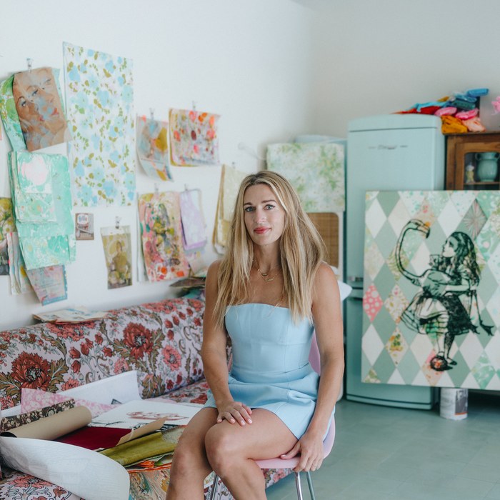 Kelly O’Connor seated in her studio surrounded by artwork.