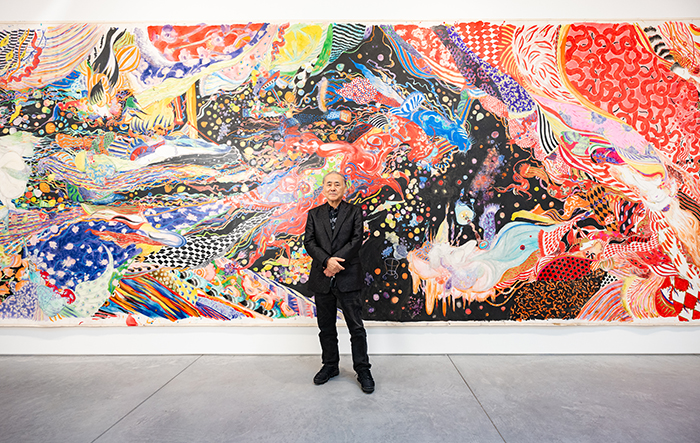 Yoshitaka Amano standing in front of his artwork.